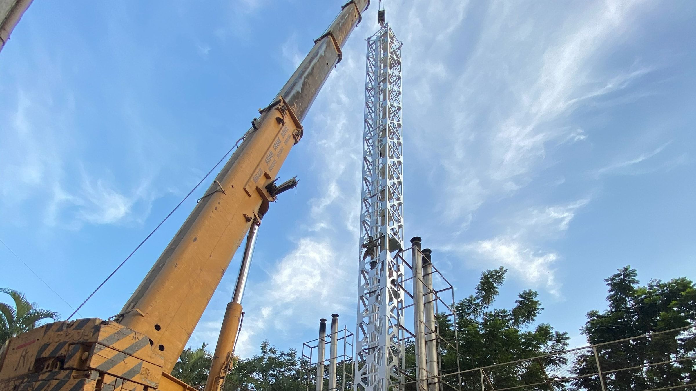 A 30-metre white lattice exhaust stack standing at an installation, with the mobile crane still rigged alongside.
