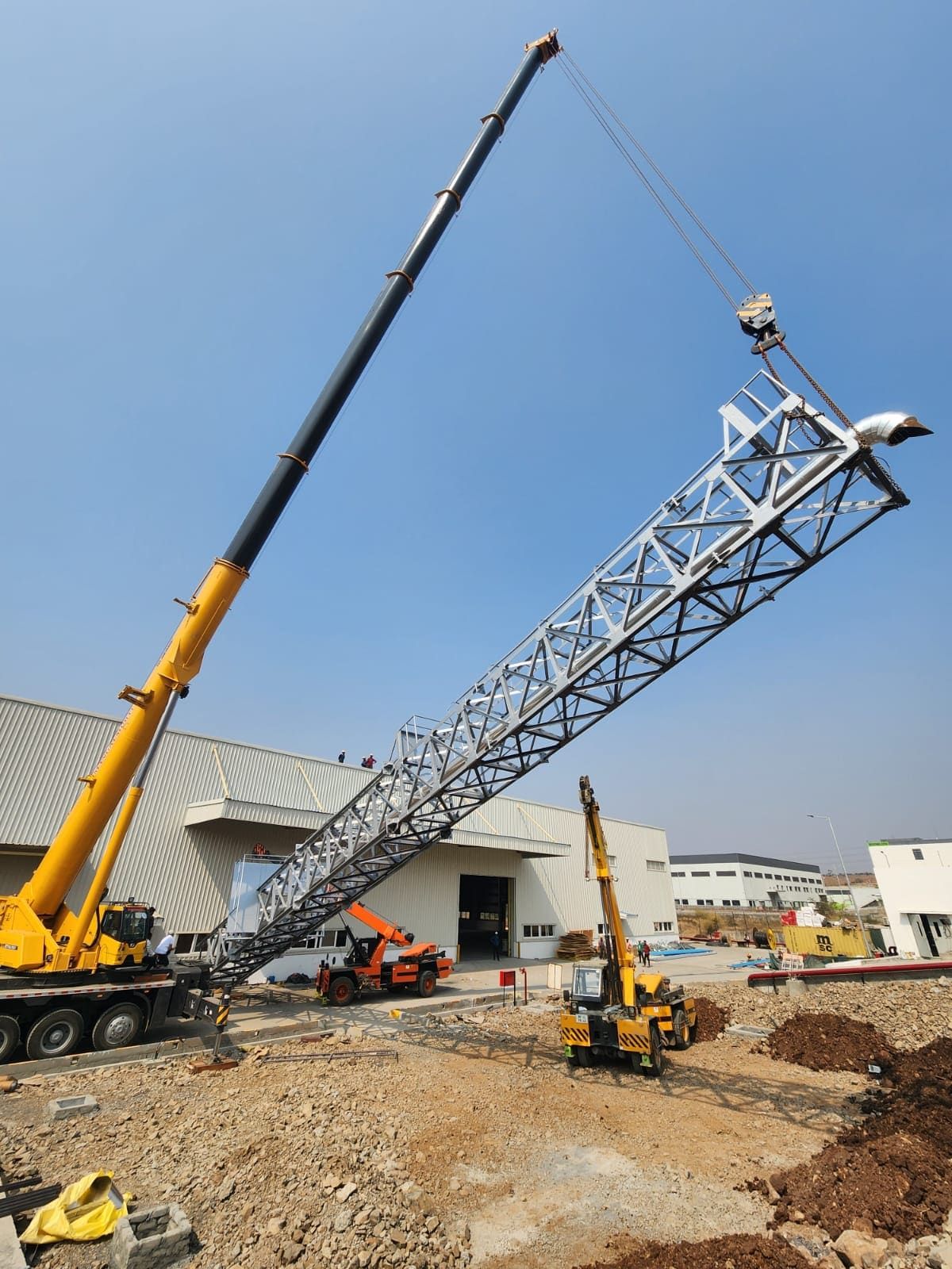 The lattice column hanging nearly vertical from the crane hook during tail-up