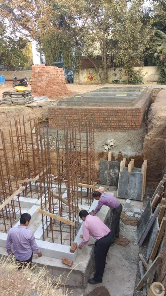 Excavated foundation pit with rebar column cages and brick shuttering