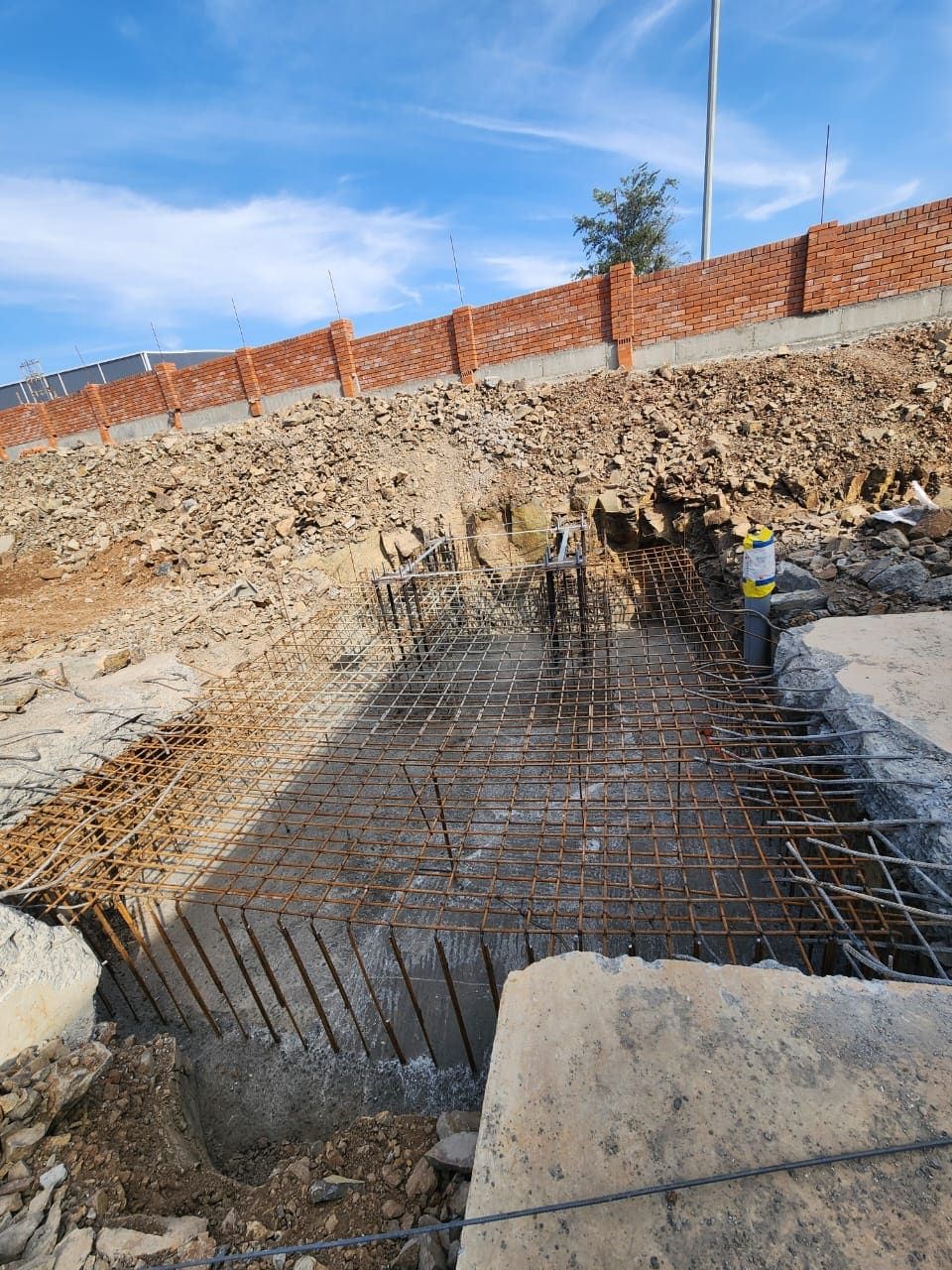 Excavated foundation with raft reinforcement and anchor cage seen from the pit edge