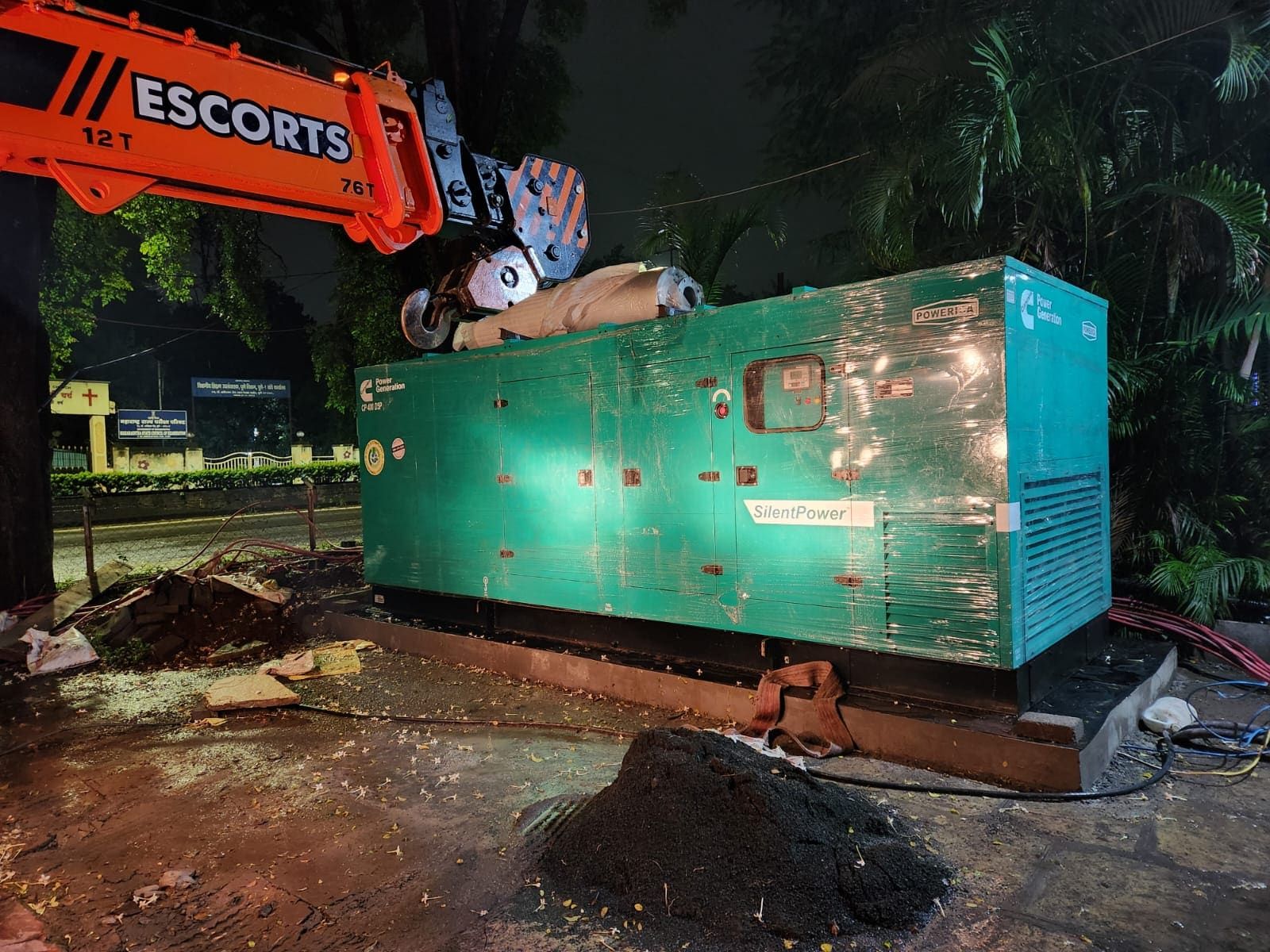 Crane placing a 400 kVA silent DG set onto its concrete plinth at night