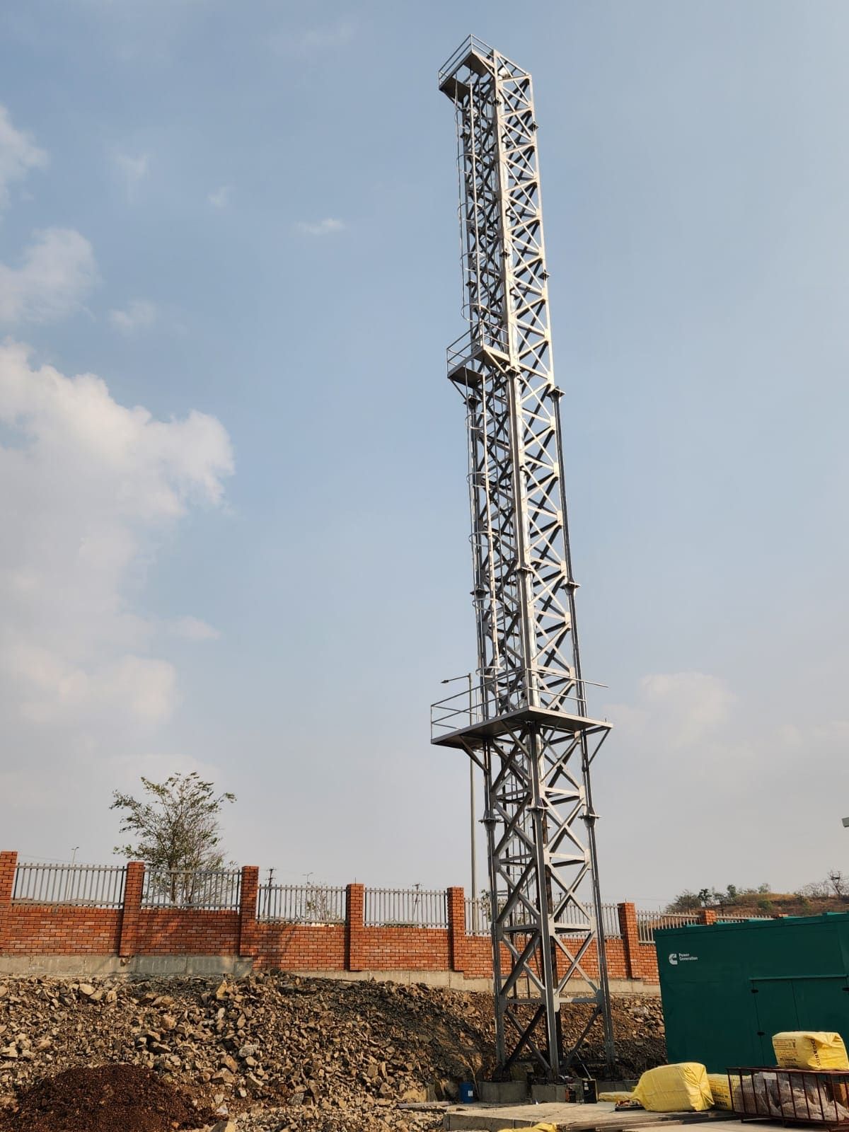 Erected lattice stack rising above a green Cummins DG canopy on rocky ground