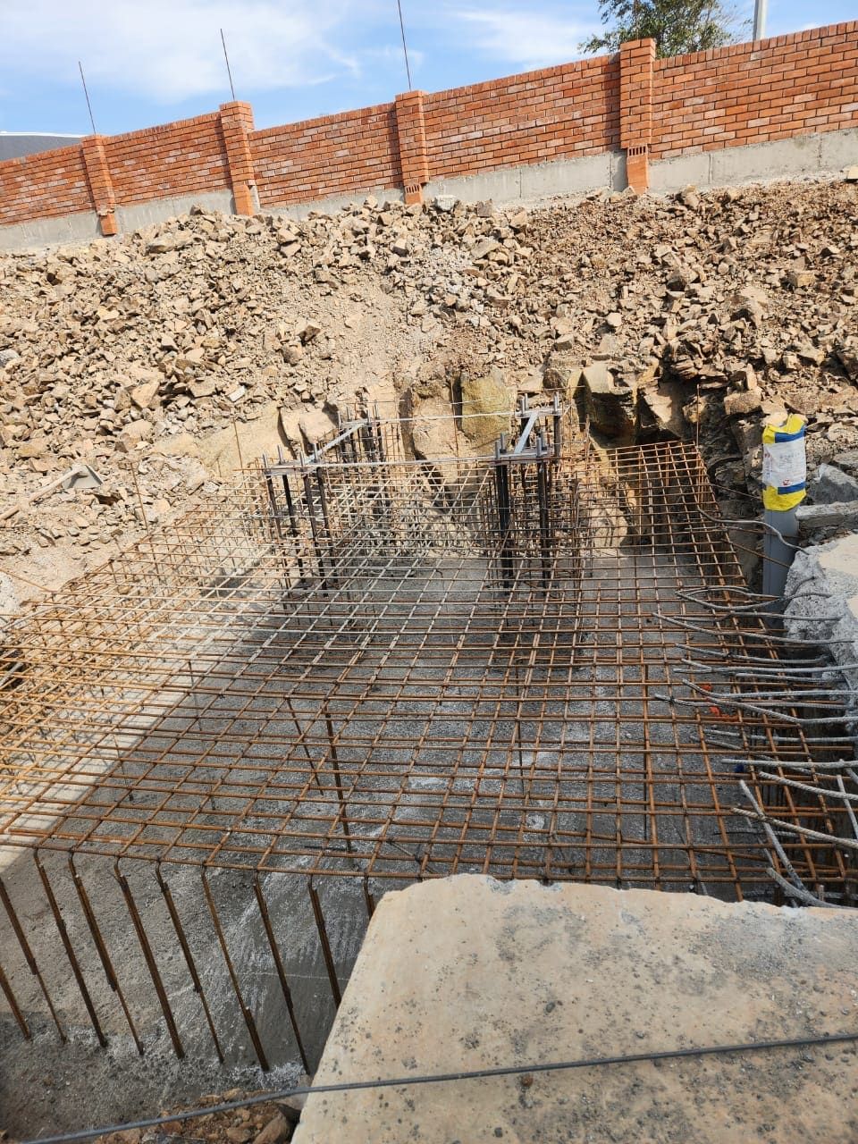 Raft reinforcement and holding-down bolt cage in an excavated stack foundation