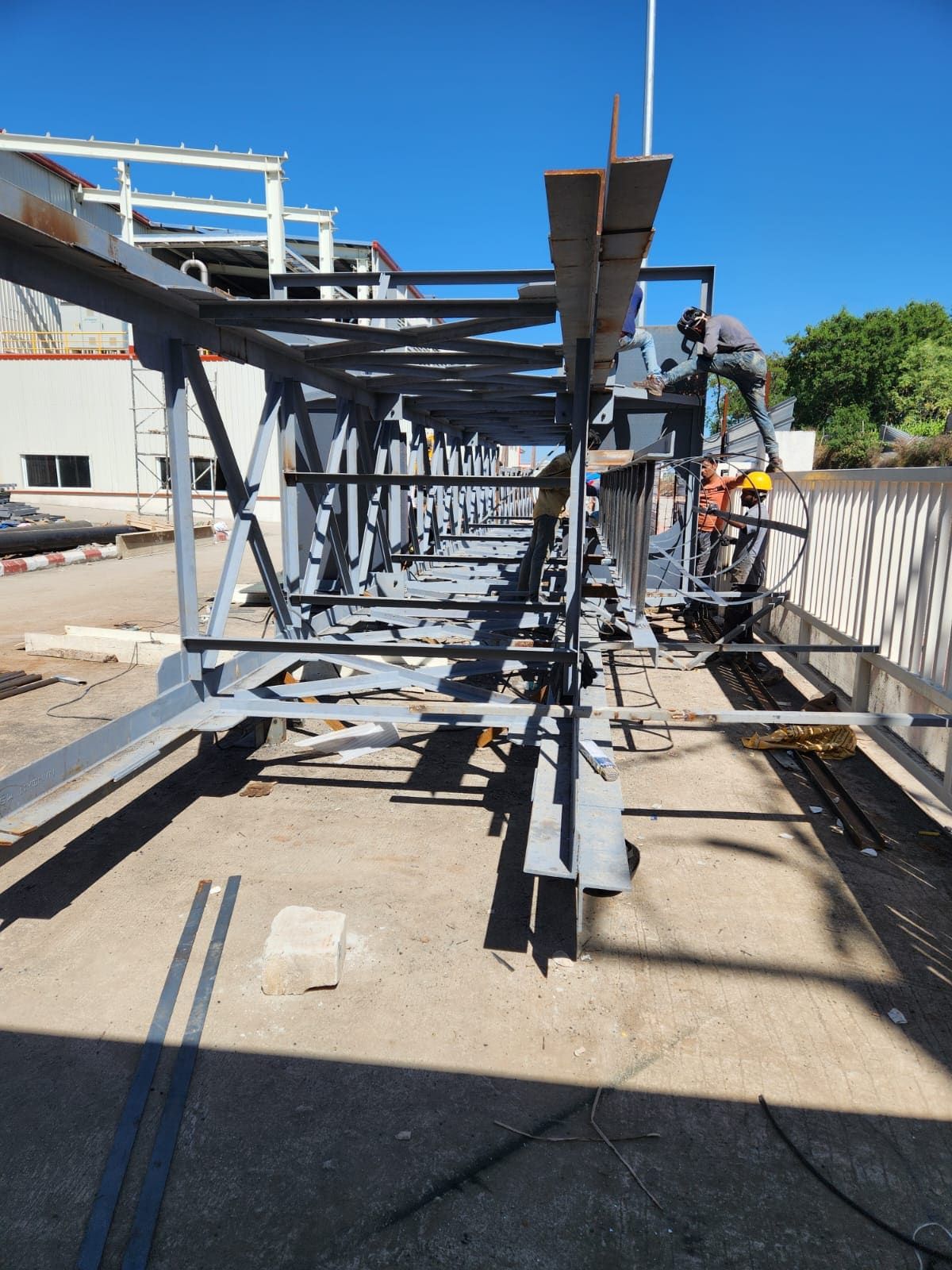 Welder working on top of a horizontal lattice stack truss during ground assembly